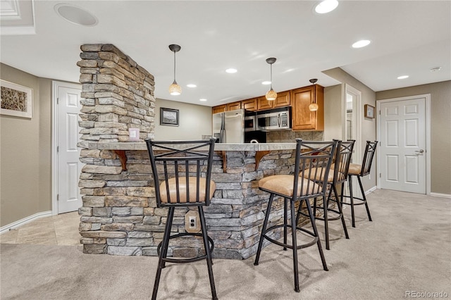 bar featuring appliances with stainless steel finishes, light carpet, and decorative light fixtures