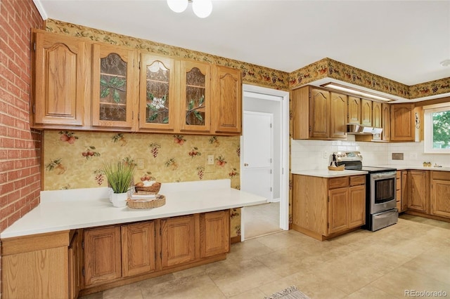 2920 S York St, Denver, CO 80210 - kitchen with stainless steel range with electric cooktop, exhaust hood, light countertops, glass insert cabinets, and brown cabinetry