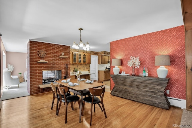 2920 S York St, Denver, CO 80210 - dining room featuring a baseboard heating unit, wallpapered walls, light wood-style floors, a fireplace, and a chandelier