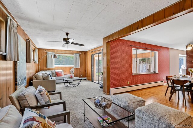 2920 S York St, Denver, CO 80210 - living room featuring a baseboard radiator, ceiling fan, wooden walls, and wood finished floors