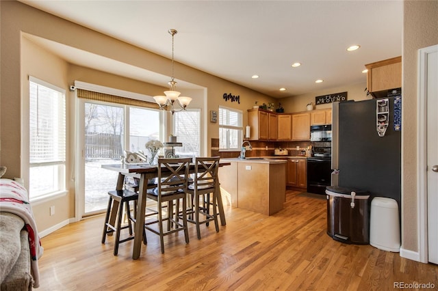 kitchen featuring a kitchen island, pendant lighting, sink, stove, and light hardwood / wood-style flooring