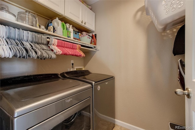 clothes washing area with cabinets and washer and clothes dryer