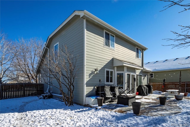 snow covered back of property with an outdoor fire pit