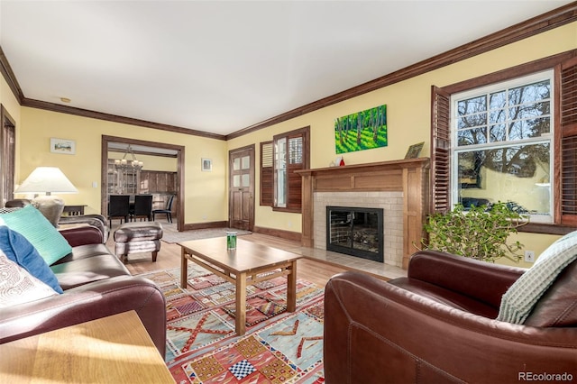 living room featuring an inviting chandelier, light wood-type flooring, crown molding, and a brick fireplace