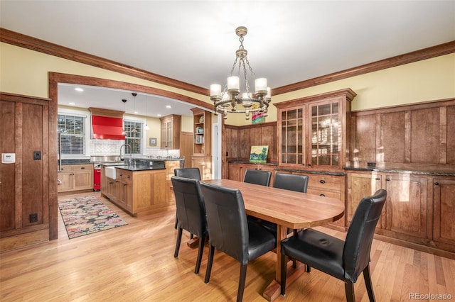 dining room featuring light wood-type flooring, ornamental molding, and a chandelier