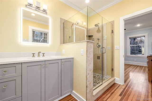 bathroom with crown molding, hardwood / wood-style floors, an enclosed shower, and sink