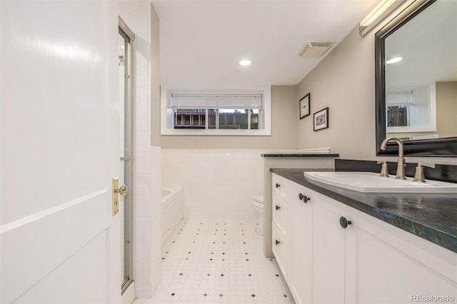 full bathroom featuring plus walk in shower, vanity, tile walls, and toilet