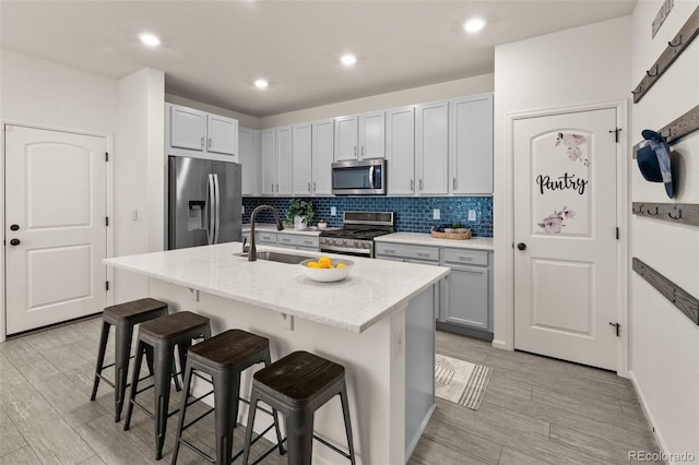 4343 S Nepal Ct, Centennial, CO 80015 - kitchen featuring appliances with stainless steel finishes, a kitchen bar, decorative backsplash, light wood finished floors, and recessed lighting