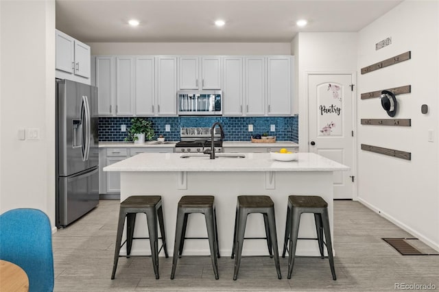 4343 S Nepal Ct, Centennial, CO 80015 - kitchen featuring appliances with stainless steel finishes, a breakfast bar area, decorative backsplash, light wood-type flooring, and recessed lighting