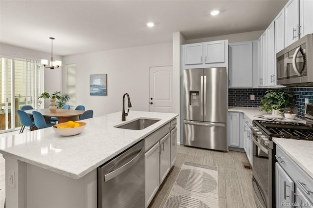 4343 S Nepal Ct, Centennial, CO 80015 - kitchen featuring stainless steel appliances, a chandelier, tasteful backsplash, light stone counters, and a center island with sink