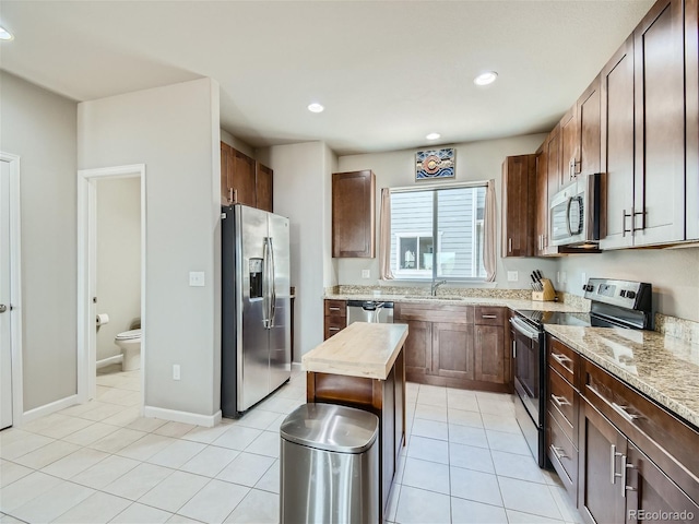 kitchen featuring light tile patterned floors, stainless steel appliances, sink, and light stone countertops