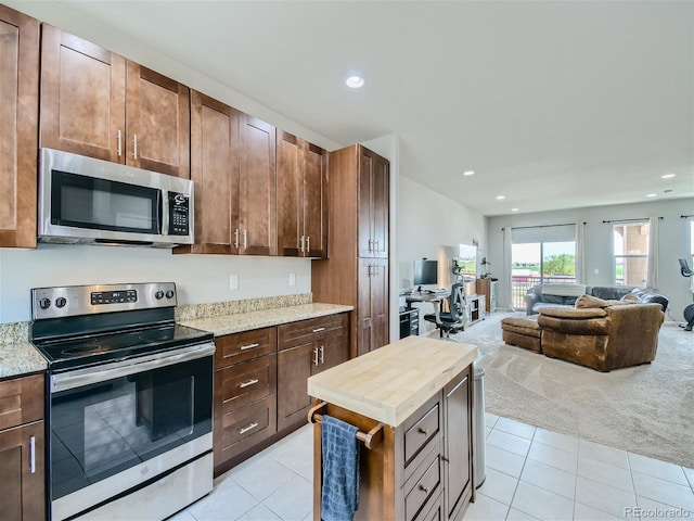 kitchen with light stone counters, recessed lighting, light colored carpet, appliances with stainless steel finishes, and open floor plan