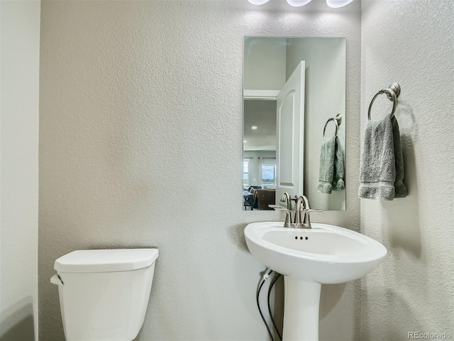 half bath with a textured wall and toilet