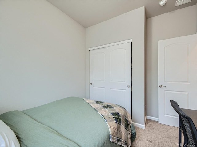 bedroom with baseboards, a closet, and light colored carpet