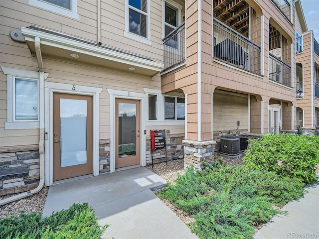 property entrance featuring stone siding and central AC