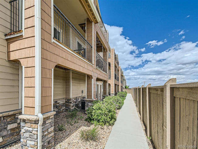 exterior space with stone siding, central AC unit, and fence