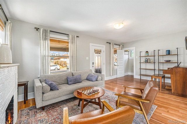 living area with a lit fireplace, baseboards, and wood finished floors