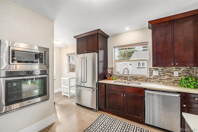 kitchen featuring light tile patterned floors, a sink, light countertops, appliances with stainless steel finishes, and tasteful backsplash