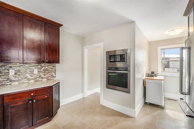 kitchen featuring decorative backsplash, stainless steel appliances, a textured ceiling, light countertops, and light tile patterned flooring