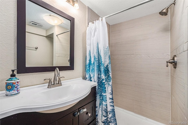 bathroom with visible vents, a textured wall, shower / tub combo, vanity, and a textured ceiling