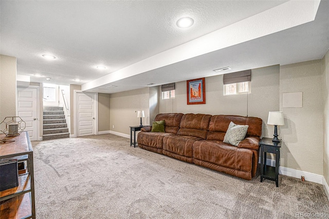 carpeted living room featuring baseboards, visible vents, stairway, and a textured ceiling