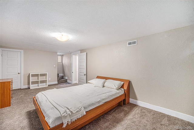 carpeted bedroom with visible vents, a textured wall, a textured ceiling, and baseboards