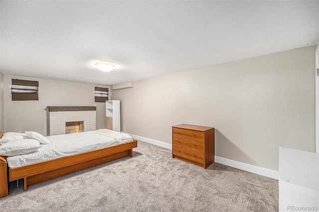 bedroom with a brick fireplace, carpet, baseboards, and a textured ceiling