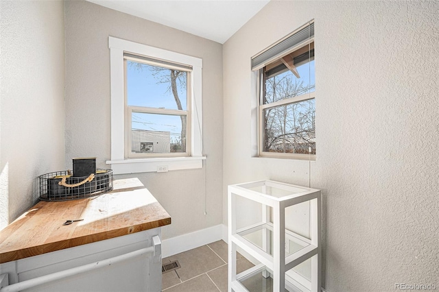 tiled home office with baseboards, visible vents, and a healthy amount of sunlight