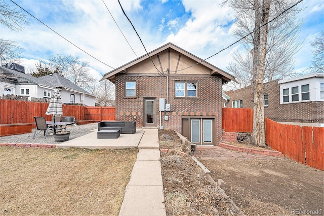 rear view of property with a lawn, a fenced backyard, a patio area, an outdoor living space, and brick siding