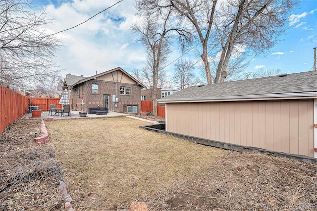 rear view of property featuring a patio area, a fenced backyard, a lawn, and brick siding