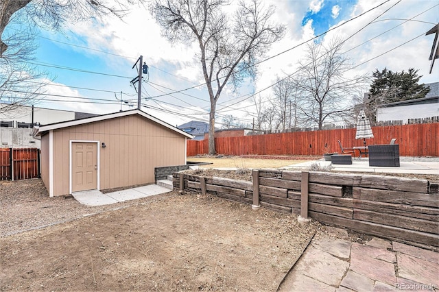 view of yard featuring a patio area, a fenced backyard, an outdoor structure, and a fire pit