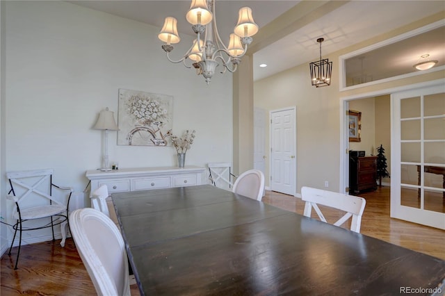 dining space featuring a chandelier, baseboards, and wood finished floors