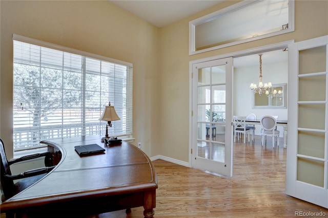 office space featuring wood finished floors, an inviting chandelier, and baseboards