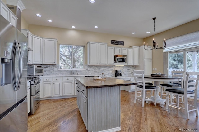 kitchen featuring wood counters, a notable chandelier, white cabinetry, and appliances with stainless steel finishes