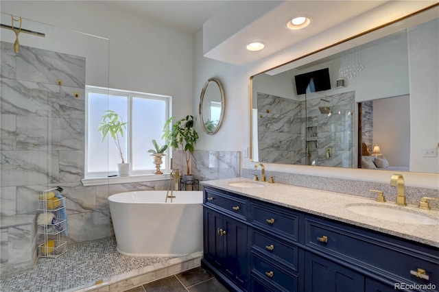 bathroom featuring a freestanding tub, tile walls, a sink, and a marble finish shower