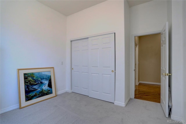 unfurnished bedroom featuring a closet, light colored carpet, and baseboards