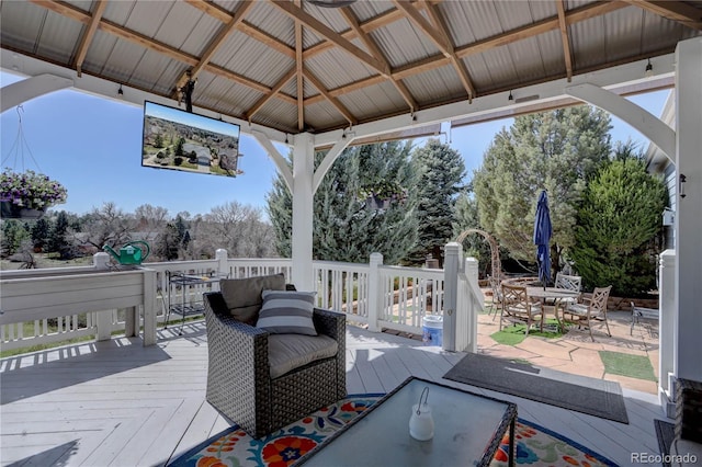 wooden terrace featuring a gazebo and outdoor dining area