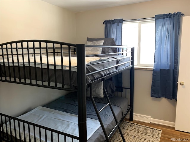 bedroom with wood-type flooring and a baseboard heating unit