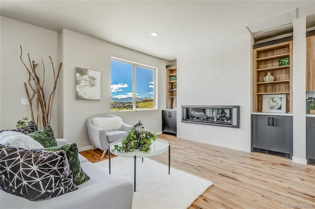 sitting room with built in features and light hardwood / wood-style flooring