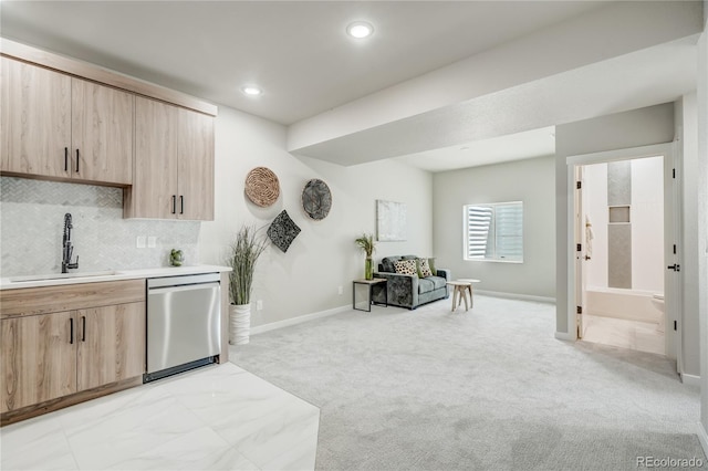 kitchen featuring decorative backsplash, light colored carpet, light brown cabinetry, dishwasher, and sink