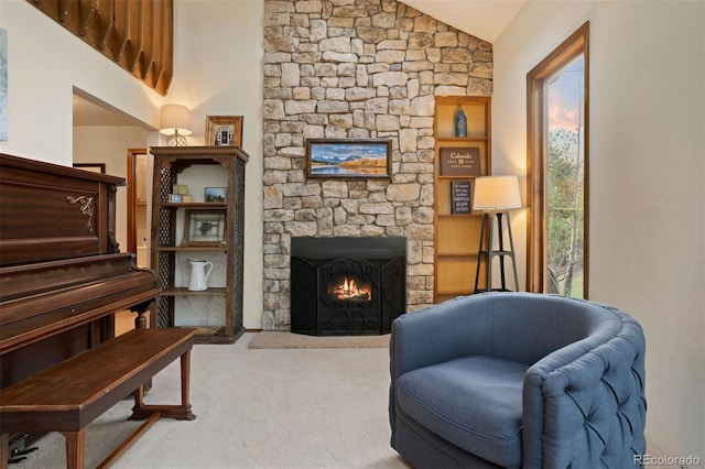 living area with a stone fireplace, light carpet, and vaulted ceiling