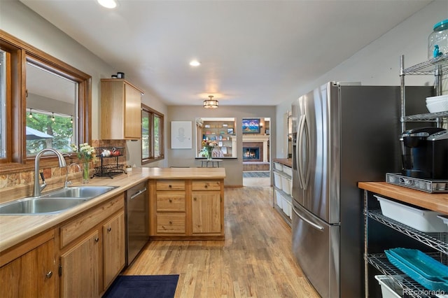 kitchen with kitchen peninsula, sink, appliances with stainless steel finishes, and light hardwood / wood-style flooring