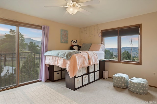 carpeted bedroom with a mountain view, ceiling fan, and access to outside