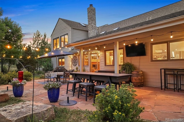 back house at dusk with a patio area