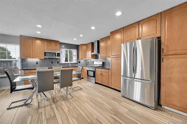 1922 Danube Way, Aurora, CO 80011 - kitchen with stainless steel appliances, wall chimney exhaust hood, healthy amount of natural light, a textured ceiling, and dark countertops