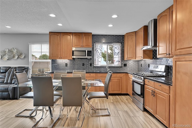 1922 Danube Way, Aurora, CO 80011 - kitchen featuring stainless steel appliances, wall chimney range hood, wood finish floors, tasteful backsplash, and recessed lighting