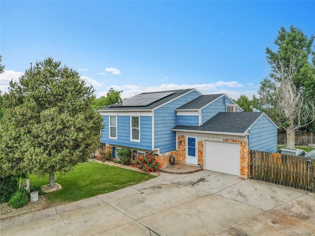 1922 Danube Way, Aurora, CO 80011 - split level home featuring solar panels, an attached garage, driveway, roof with shingles, and stone siding