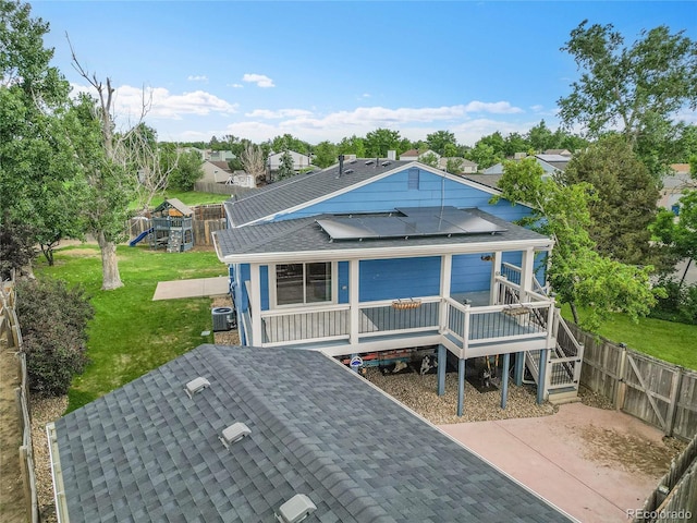 1922 Danube Way, Aurora, CO 80011 - view of front of home with solar panels, a shingled roof, a fenced backyard, and a wooden deck