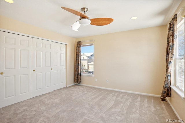 unfurnished bedroom with ceiling fan, light colored carpet, and a closet