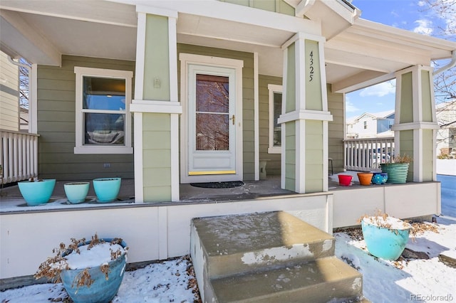 snow covered property entrance with a porch